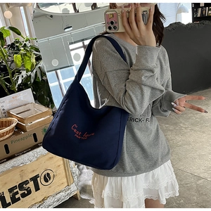 Détail du sac cabas en toile bleu marine avec broderie rouge et bandoulière robuste