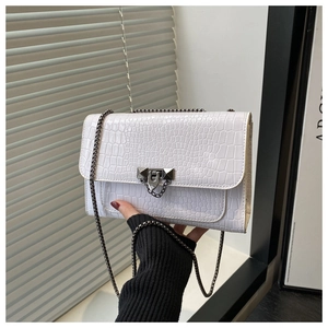 Detail shot of white crocodile embossed leather flap bag with dark metal chain strap