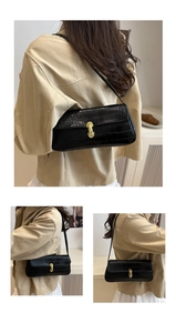 Detailed view of black crocodile pattern baguette bag with golden U-shaped metal buckle