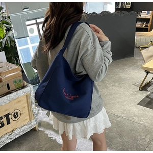 Détail du sac cabas en toile bleu foncé avec broderie rouge et bandoulière large