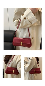 Detail of dark red crocodile pattern baguette bag with shiny gold metal oval buckle