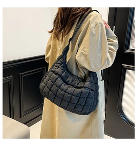 Close-up of a black quilted tote bag with a checkered pattern and long shoulder strap