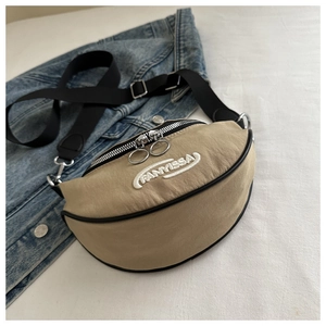 Détail du sac banane beige en croissant avec broderie FANYISSA et bandoulière noire