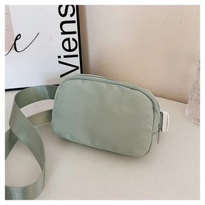 Detail of adjustable wide fabric strap and nylon material on green crossbody waist bag