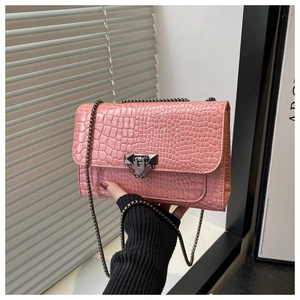 Close-up of pink croc-embossed small square bag with metallic chain and twist lock