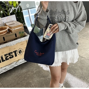Détail du sac cabas en toile bleu marine avec broderie rouge et bandoulière robuste