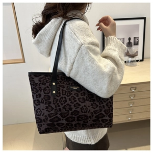 Detail view of leopard print tote bag with black leather straps and gold rivets