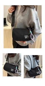 Détail du sac polochon en nylon noir avec broderie de lettres et breloque tissée