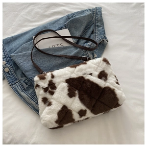 Détail du sac bandoulière en peluche à motif vache avec texture matelassée et sangle