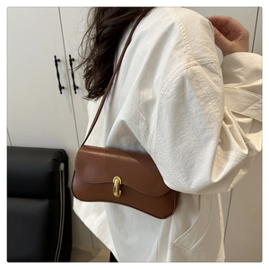 Détail d'un sac porté épaule marron en forme de croissant avec fermoir tournant doré