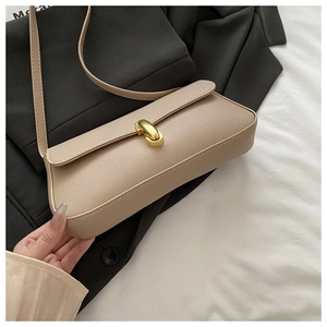 Dettaglio della borsa a spalla in pelle martellata beige con chiusura metallica d'oro