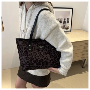 Close-up of leopard print tote bag featuring a brand metal logo and sleek black straps