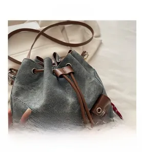 Detail of washed denim bucket bag with brown leather drawstring and metal eyelets
