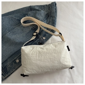 Detail of white nylon crossbody bag with adjustable strap on blue denim jacket
