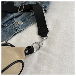 Détail de la bandoulière en nylon noir avec crochet argenté sur un sac en toile