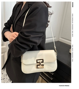 Detail of elegant cream shoulder bag with golden double-ring buckle shown on a model