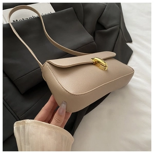 Dettaglio borsa sottobraccio in pelle beige motivo litchi con fibbia girevole in metallo oro