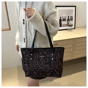 Detailed view of leopard print tote bag with black leather straps and gold rivets
