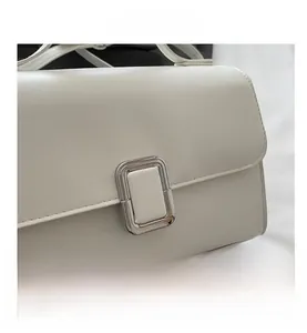 Close-up of creamy white faux leather shoulder bag with a polished silver rectangular clasp