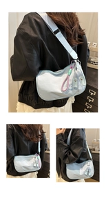 Détail du sac bandoulière bleu clair avec broderie et breloque tressée violette