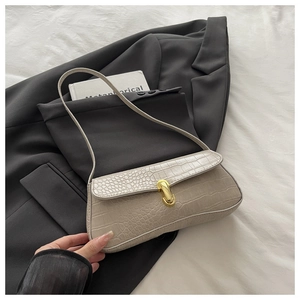 Close-up of beige crocodile pattern baguette bag with gold U-shaped metal buckle