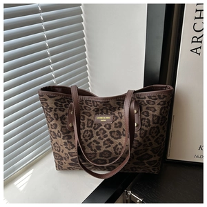Close-up of leopard print tote bag with brown leather handles and brand logo detail