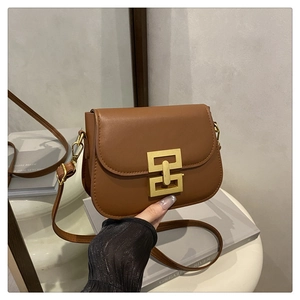 Close-up of brown leather crossbody bag with a modern interlocking gold metal buckle