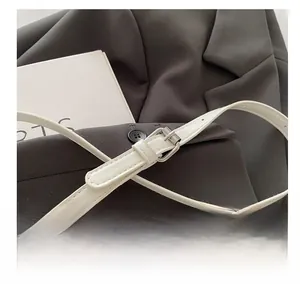 Detail shot of the adjustable white leather shoulder strap and silver metal buckle