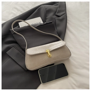 Detail of cream baguette bag featuring crocodile texture and golden U-shaped lock