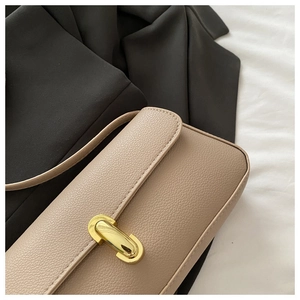Dettaglio della borsa a tracolla in pelle martellata beige con fibbia ovale dorata