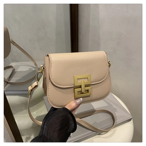 Detail shot of beige small square bag featuring a gold geometric metal clasp closure