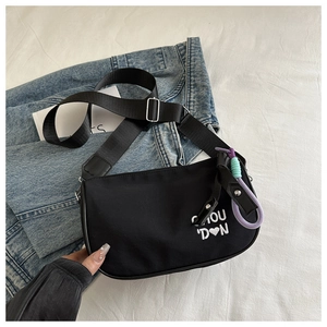 Détail du sac à bandoulière noir avec broderie coeur blanc sur surface en tissu
