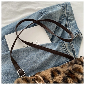 Gros plan du sac en peluche léopard avec bandoulière marron sur une veste en jean