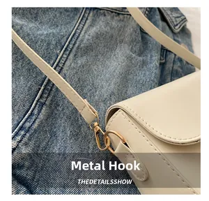 Close-up of golden hardware hook and cream leather strap on a stylish crossbody bag