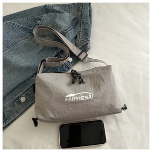 Top view of a light gray nylon crossbody bag with dual zippers and adjustable strap