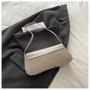 Detail of beige baguette bag with crocodile embossed texture on a dark grey blazer background