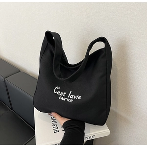 Détail d'un sac cabas en toile noire avec texte blanc sur un livre blanc
