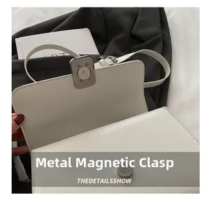 Detail of white leather shoulder bag featuring a high-quality magnetic snap closure