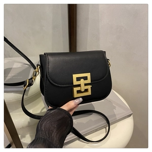 Detailed close-up of matte black leather bag with interlocking gold geometric metal buckle
