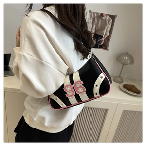 Detail of retro black shoulder bag with pink piping and number 96 patch on a model