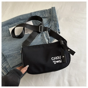 Détail d'un sac bandoulière en nylon noir avec broderie blanche de lettres et de cœur
