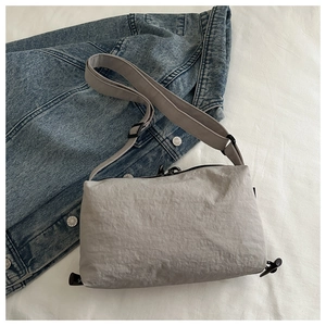 Detail of light grey nylon dumpling bag with wrinkled texture and adjustable shoulder strap