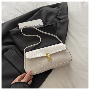 Detailed view of white crocodile pattern leather texture and gold buckle on baguette bag
