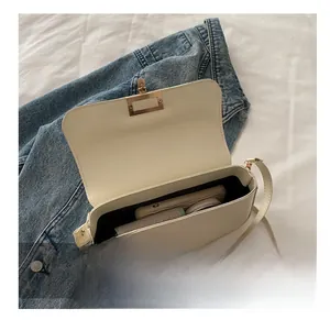 Detail view showing interior capacity of a white leather crossbody bag with gold hardware