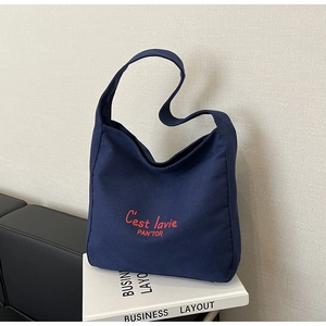 Detail of navy canvas tote bag featuring red C'est lavie art text on a textured surface
