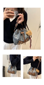 Detail view of denim bucket bag with brown leather drawstring and striped scarf charm