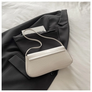 Detail of creamy white baguette bag with crocodile texture on grey blazer