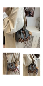 Detail view of canvas drawstring bucket bag with leather trim and plush ball charm