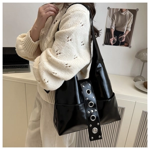 Detalle del bolso tote negro brillante con ojales metálicos vintage y remaches punk