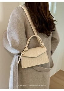 Detailed side view of cream woven crossbody bag styled with a minimalist wool coat